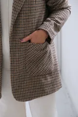Blazer de corte recto con estampado de cuadros tipo príncipe de gales en tonos marrones y beige. Presenta solapas clásicas, bolsillos frontales aplicados y mangas largas.