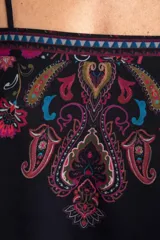 Top corto negro con tirantes finos, escote recto y diseño holgado. Presenta un estampado estilo paisley con detalles en tonos fucsia, turquesa y verde, además de una cenefa geométrica en la parte superior.
