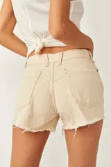 Short de denim color beige, de tiro medio y silueta relajada, con cinco bolsillos, cierre frontal con botón y cremallera, y detalles de roturas y bordes deshilachados.
