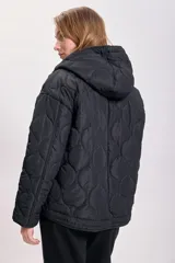 Campera capitoneada negra con diseño acolchado, cierre frontal con botones a presión, capucha con cordón ajustable y cordón en el ruedo.