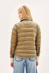 Campera puffer de corte camisero en color verde militar, con cierre frontal mediante botones a presión, bolsillos superiores con solapa y puños tejidos en color beige.