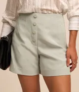 Short de sastrería color rosado, de tiro alto con detalles de pinzas frontales y cartera abotonada con cuatro botones revestidos. Presenta diseño recto y estructurado.