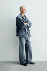 Parka de denim de algodón con efecto lavado, de color azul medio. Presenta cuello solapa, manga larga con puño abotonado, cierre frontal de botonadura oculta y cintura ajustable con cordón interior. Posee cuatro bolsillos utility de plastrón con solapa: dos en el pecho y dos en la cadera.