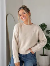 Sweater de punto color beige con diseño de cuello redondo, mangas largas y detalles de pequeñas roturas decorativas en el frente y las mangas. Presenta puños y ruedo acanalados.