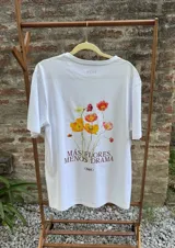 Remera blanca de manga corta, confeccionada en algodón premium, con estampa central de flores coloridas y la frase 'Más flores, menos drama'.
