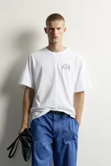 Remera de corte relaxed fit, color blanco, con cuello redondo y manga corta. Presenta un pequeño estampado en contraste en el pecho.