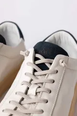 Championes urbanos de cuero blanco con suela de goma color caramelo y detalle de talón en color azul oscuro.