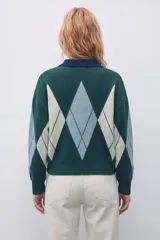 Sweater de tejido de punto con diseño de rombos en tonos verde inglés, gris y beige. Presenta cuello polo con cierre de botones, mangas largas y corte holgado.