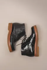 Bota acordonada de cuero vacuno con acabado charol color suela, con suela de goma tipo crepe y costuras reforzadas.