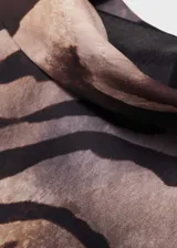 Vestido corto de cuello drapeado y manga larga, confeccionado en tejido fluido con acabado satinado. Presenta un diseño evasé con estampado de cebra y cierre de cremallera en la parte posterior.