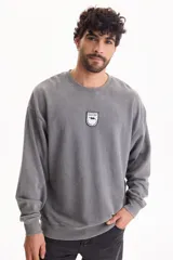 Buzo gris con efecto lavado, cuello redondo, mangas largas y un pequeño parche bordado en el pecho con la leyenda "Find Joy".