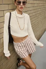 Shorts de denim de tiro bajo con diseño de rayas verticales en tonos rosado y marrón, cinco bolsillos, cierre frontal con cremallera y botón, y detalle de cintura desflecada.