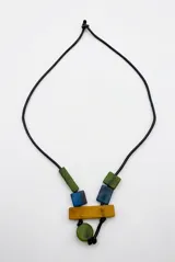 Colgante de diseño geométrico con cordón negro y piezas de resina en tonos azul, verde y mostaza.