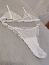 Conjunto de lencería compuesto por un corpiño triangular y una bombacha tipo colaless, confeccionados en encaje con diseño de ondas y detalles en satén.