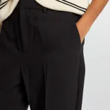 Pantalón negro de vestir, corte pitillo, con bolsillos laterales y traseros.