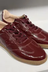 Championes de cuero vacuno con acabado brillante tipo charol, color azul marino, con cordones al tono y suela de goma color caramelo.