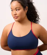 Top deportivo Get Over de corte nadador, confeccionado en microfibra azul marino con detalles en color rojo en los bordes y breteles. Presenta escote en U y copas integradas.