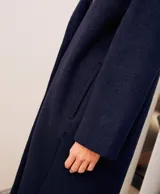 Abrigo oversize color ladrillo, confeccionado en lino pesado, con botonadura simple, bolsillos con solapa y ventilación trasera.