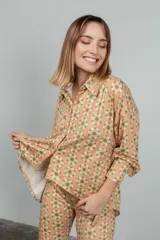 Camisa de manga larga color rosado con estampado de flores anaranjadas y blancas.