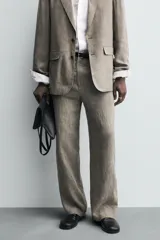 Pantalón de corte straight relaxed fit confeccionado en tejido de lino con efecto lavado. Presenta cierre frontal con cremallera y botón, bolsillos laterales y bolsillos traseros de vivo.
