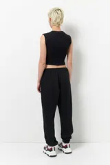 Babucha deportiva de corte holgado, color negro, con cintura elástica ajustable mediante cordones y puños elásticos en los tobillos. Cuenta con bolsillos laterales.