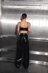 Pantalón negro de charol con tiro medio alto, botón metálico níquel, badana de RENÉE en cintura y bolsillos traseros.