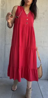 Vestido midi rojo sin mangas con botones decorativos en el escote y corte escalonado.