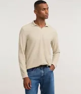 Polo de manga larga color beige claro, confeccionado en tejido texturizado (posiblemente acanalado o waffle). Presenta un cuello polo con escote profundo en V sin botones.