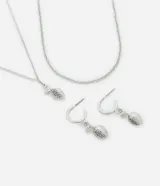Conjunto de accesorios de metal plateado compuesto por una gargantilla de cadena, un collar con dije colgante en forma de limón con incrustaciones de strass y un par de aros tipo argolla con dijes de limón colgantes.