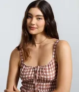 Vestido corto evasê de viscosa con estampado de cuadros vichy en tonos rosado y blanco. Presenta breteles anchos, escote cuadrado, lazo ajustable en el busto y falda con volados.