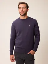 Sweater de punto con cuello redondo, manga larga y puños acanalados. Presenta un pequeño logo bordado en el pecho.