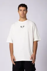 Remera de corte oversize color blanco hueso, con cuello redondo y estampa pequeña centrada en el pecho que presenta dos figuras de caballos alados.