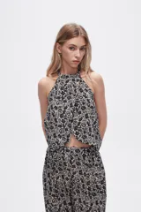 Top cropped de viscosa con estampado paisley en tonos negro y beige, diseño sin mangas con cuello halter y detalle de lazada.
