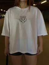 Remera blanca oversize de manga corta, con cuello redondo y diseño gráfico de araña en el pecho.