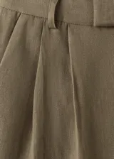 Pantalón de lino verde militar, de diseño recto y tiro alto, con detalle de pinzas y trabillas en la cintura.