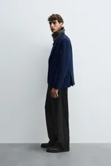 Blazer azul marino de corte recto, confeccionada en tejido con viscosa. Tiene cuello con solapas de muesca, manga larga con puño abotonado, bolsillo de vivo en el pecho y bolsillos de parche en la cadera. El bajo tiene aberturas en la espalda y el cierre es con botonadura frontal.