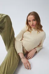 Sweater color crema de tejido de punto acanalado, corte cropped, cuello redondo y mangas largas.