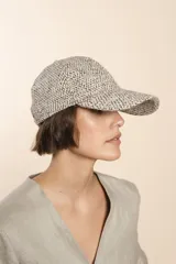 Gorra con visera confeccionada en lana fina sin teñir, con un sutil patrón de tejido en espiga.