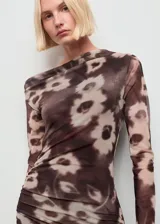 Vestido midi de manga larga con cuello asimétrico y diseño entallado. Presenta un estampado floral en tonos marrones y beige, con detalle drapeado en la cintura y forro interior.
