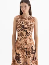 Vestido midi sin mangas con estampado de dragones en tonos marrones. Presenta cierre frontal con botones, falda amplia con gajos, recortes estilo jeanero, canesú y bolsillos laterales.