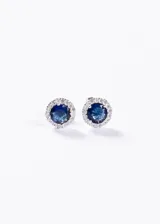 Aros tipo botón de plata 925 hipoalergénica, con una piedra central redonda de zirconia azul rodeada por un halo de zirconias blancas más pequeñas.