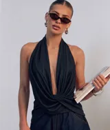 Top halter negro con escote en V profundo y detalle drapeado cruzado en la cintura.