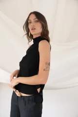 Remera blanca sin mangas con cuello alto y detalle de frunces laterales con cordones.