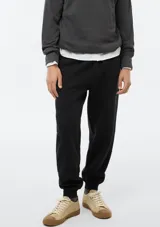 Pantalón tipo babucha de color azul oscuro, confeccionado con interior de felpa. Presenta cintura elástica con cordón de ajuste y puños acanalados en los tobillos.
