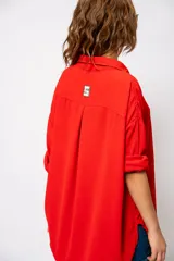 Camisa roja amplia de manga larga con ruedo curvo.