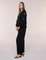 Blusa azul de corte holgado y fluido, con escote en V y mangas largas raglán que presentan detalles de calados con forma de flores y puños elastizados.