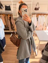 Cartera tipo baguette con estampado animal print, confeccionada en material suave símil gamuza. Presenta un bolsillo frontal con solapa y cierre, compartimento principal con cierre superior, y asa larga regulable de cuero sintético marrón.