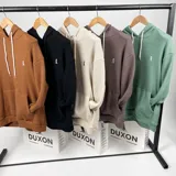 Canguro oversize color crema con capucha y bolsillo delantero tipo canguro.