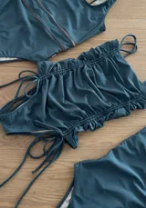 Top de bikini color verde petróleo con diseño fruncido en la parte superior e inferior, y tiras laterales ajustables.