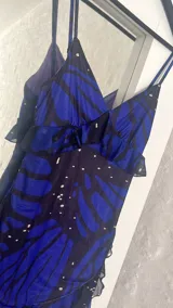 Vestido corto con estampado de mariposas azules y negras, escote en V con volantes y tirantes finos.